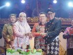 Bupati Berau Sri Juniarsih (kiri) menyerahkan potongan tumpeng ke Rusmadi Wongso.